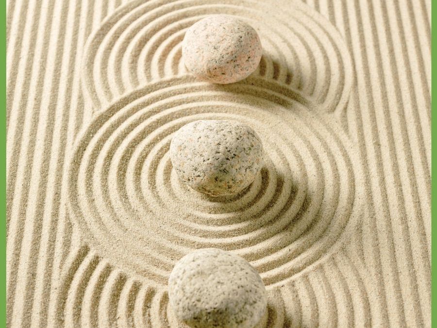 Three stacked stones on raked sand