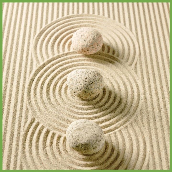 Three stacked stones on raked sand