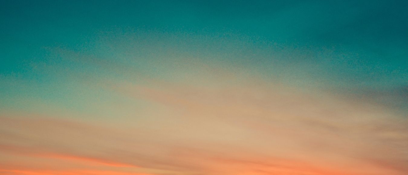 Teal-to-orange sunset over dark hills