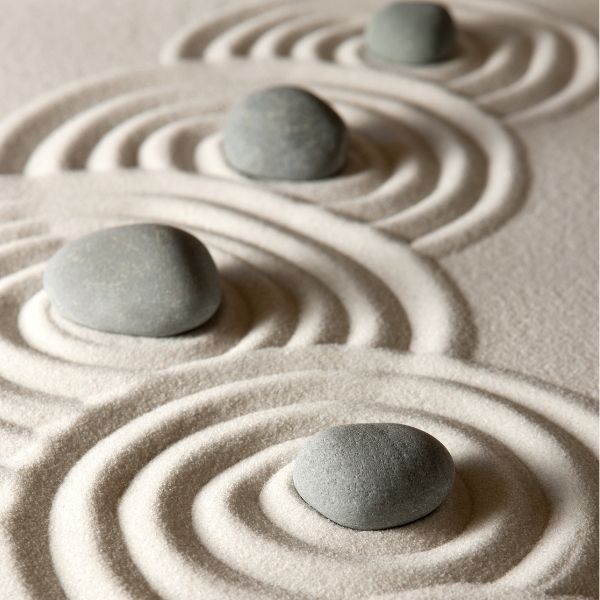 Three stones on raked sand in warm natural light
